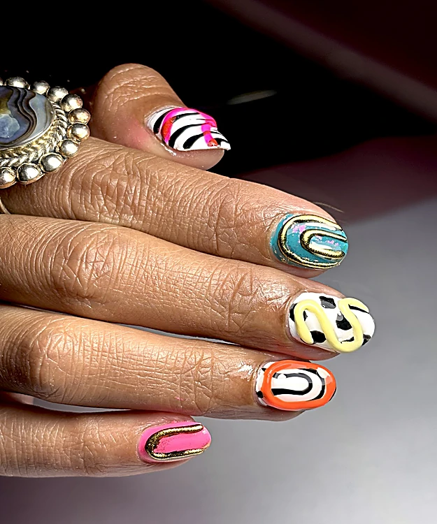 Uñas con diseño abstracto en naranja, rosa, turquesa y dorado sobre fondo oscuro