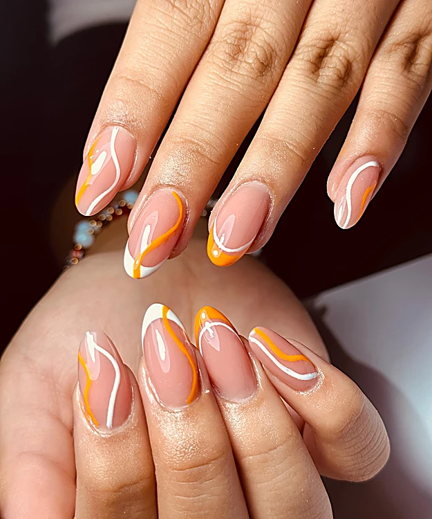 Uñas almendra nude con líneas onduladas naranjas y blancas
