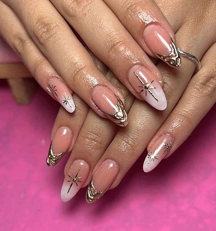 Uñas almendra nude con detalles metálicos dorados y estrellas