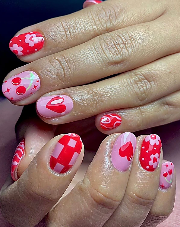 Uñas cortas rojas y rosas con cerezas, corazones, flores y cuadros