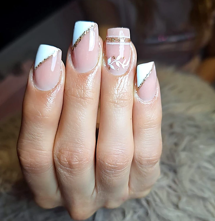 Uñas cuadradas en francés blanco diagonal con línea de brillo dorado y una flor fina