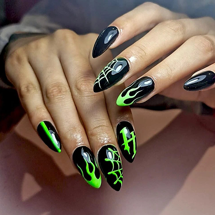Uñas stiletto negras con llamas y telarañas en verde neón