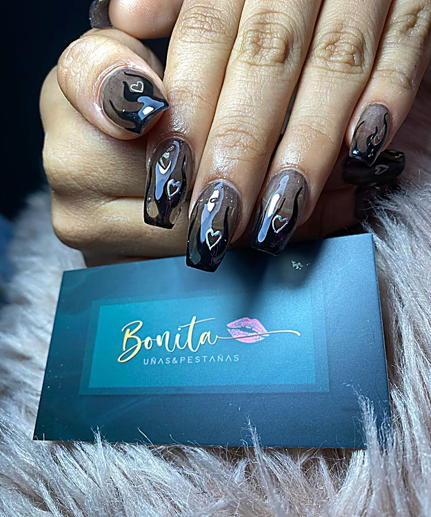 Uñas negras translúcidas con corazones, sobre la tarjeta de Bonita