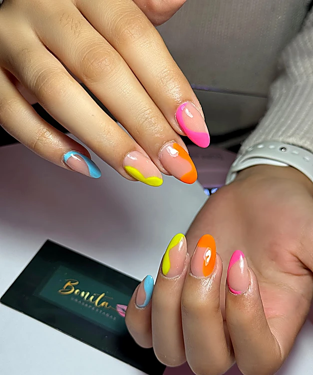 Uñas con puntas francesas en colores neón: rosa, naranja, amarillo y azul